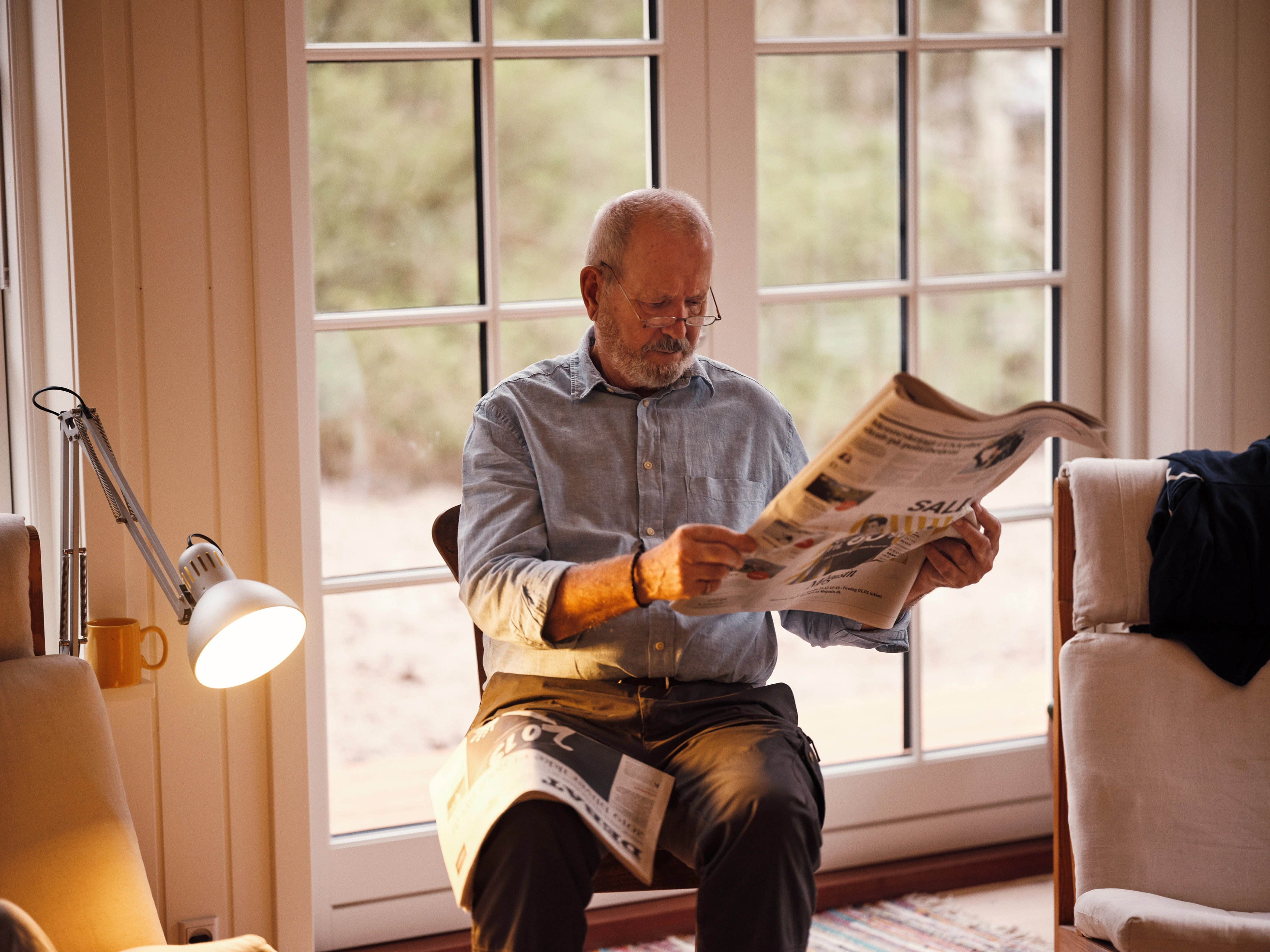  Pensionist læser nyheder fra avisen i sin stue